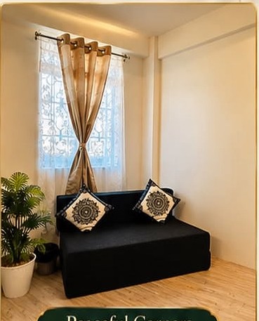 Quiet sitting nook with a sofa beside a bright curtained window